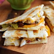 Two chicken fajita quesadilla wedges stacked on a board.