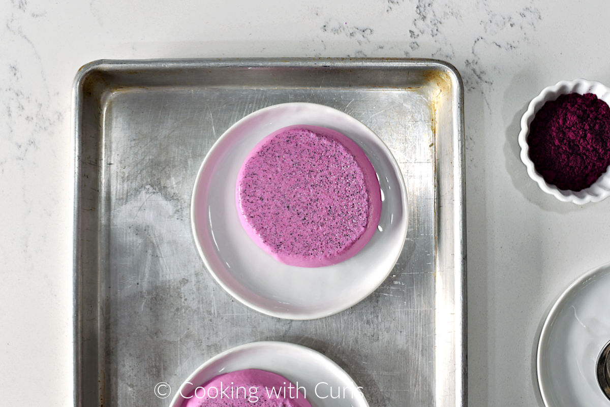 Dragon Fruit Panna Cotta on a small plate with a small bowl of dragon fruit powder on the side. 