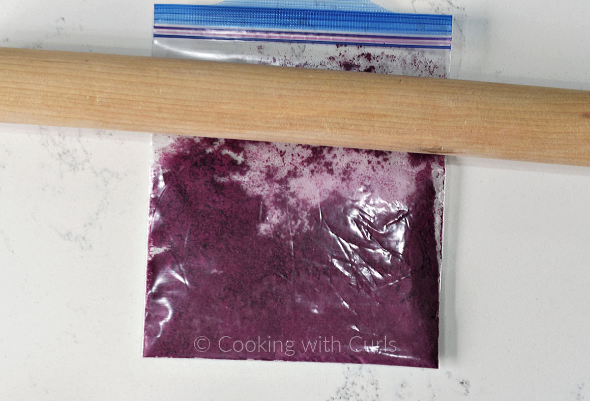 Dragon fruit powder in a zipper top bag with a rolling pin on top. 