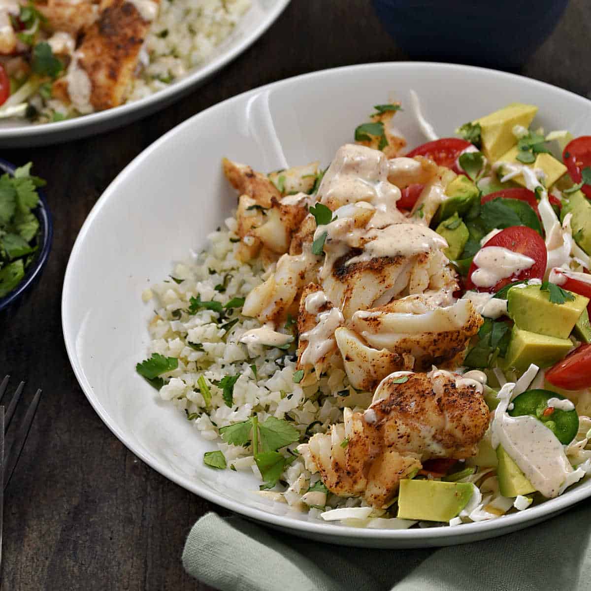 Fish Taco Bowls on a bed of cilantro-lime rice drizzled with cilantro-lime sauce.