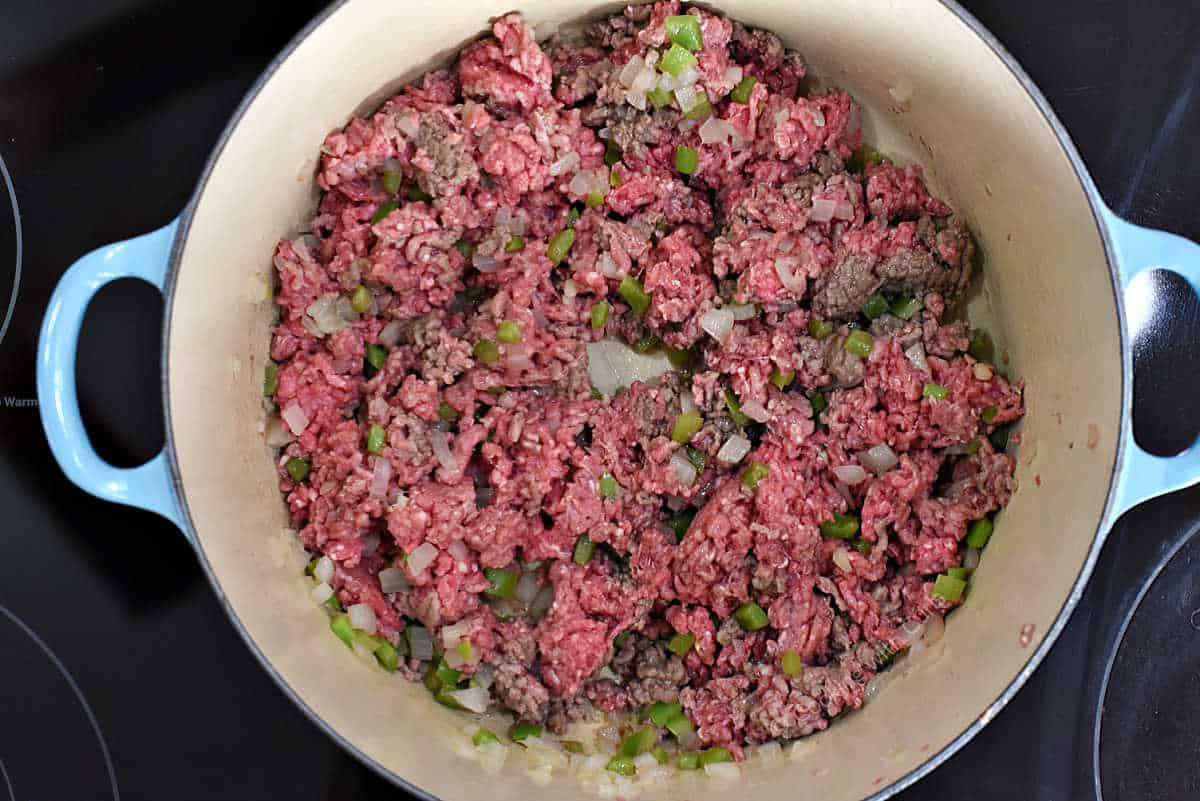 Ground beef and sautéed veggies cooking in dutch oven.