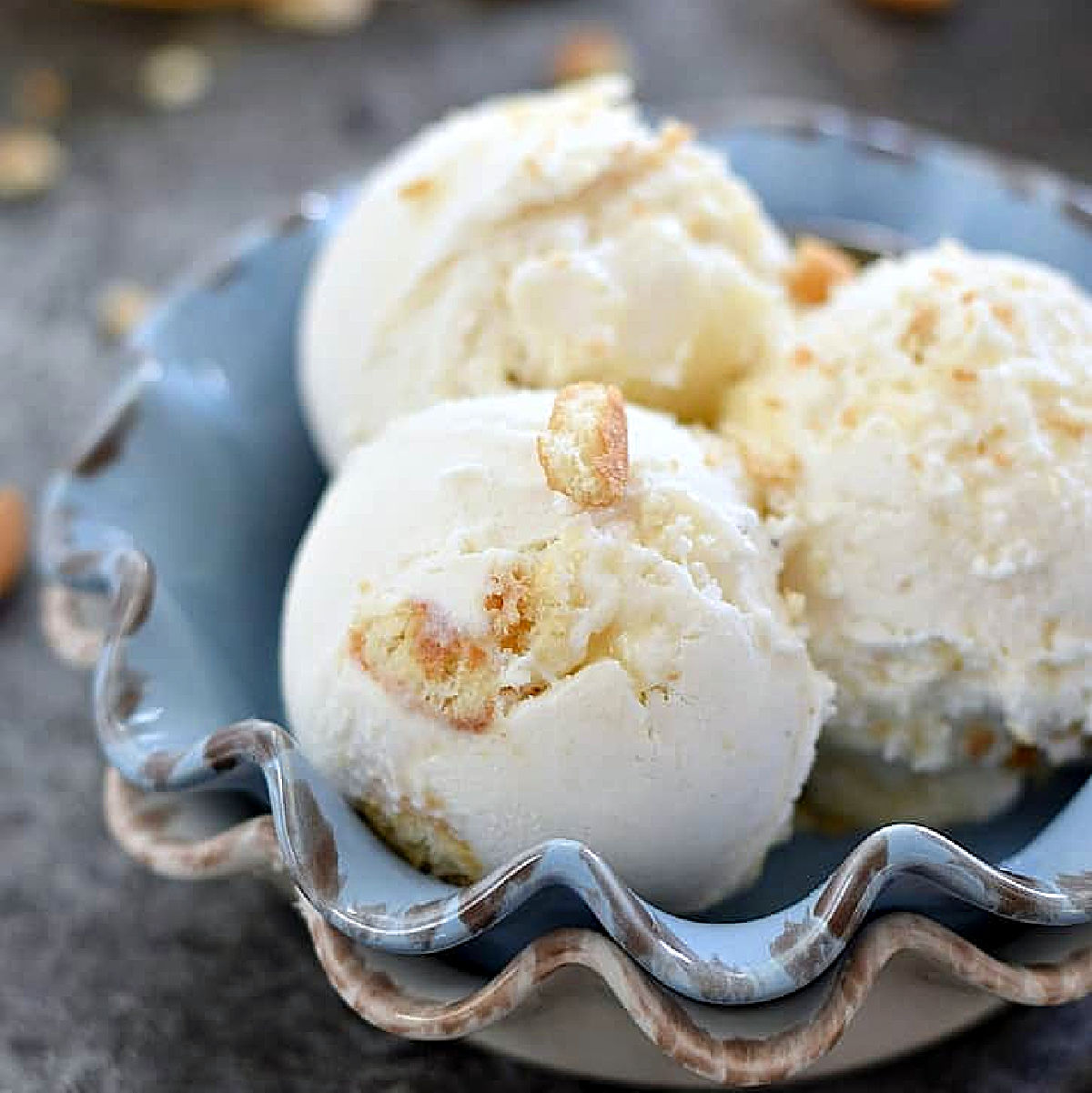 Three scoops of lemon cheesecake ice cream in a blue bowl.