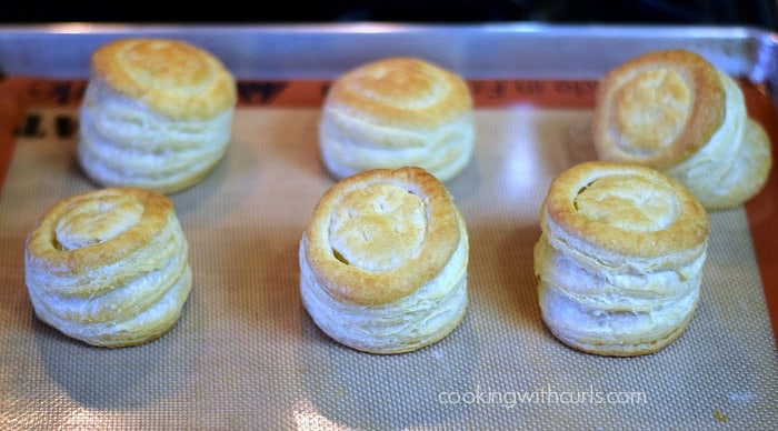 Six baked puff pastry shells on a silicone lined baking sheet.