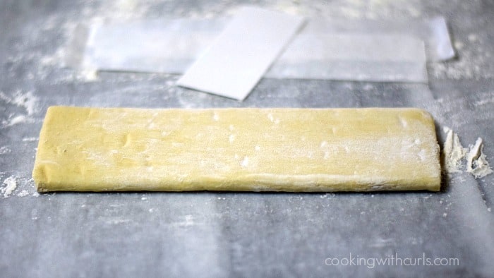 A folded sheet of puff pastry on a flour covered marble board.