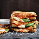 one and a half Pizza Margherita Grilled Cheese sandwiches stacked on top of each other with a fourth sitting next to the stack.