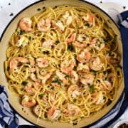Looking down on shrimp and linguine pasta tossed with garlic, lemon, and wine sauce in a large skillet.