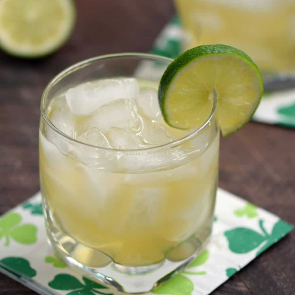 irish whiskey cocktail garnished with a lime wheel sitting on a shamrock covered napkin