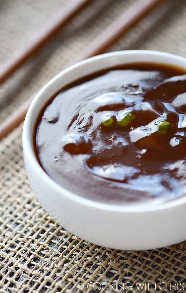 small white bowl filled with sweet and sour sauce sitting on a natural mesh placemat