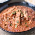 a big black bowl of Tikki Masala with white rice and pita bread in the background